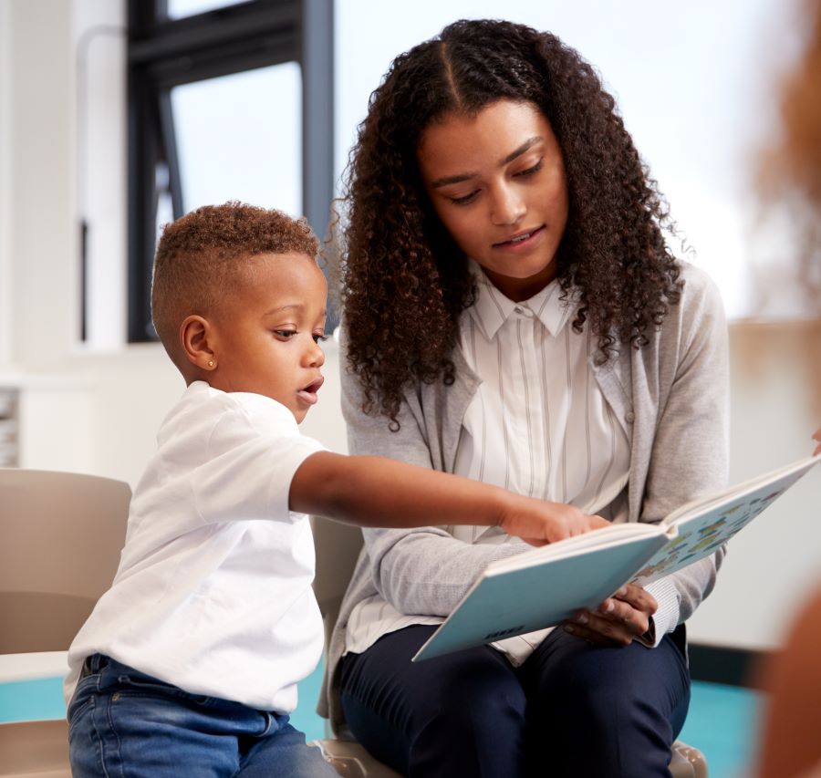 Jonge vrouw leest kleine jongen voor uit een boek.