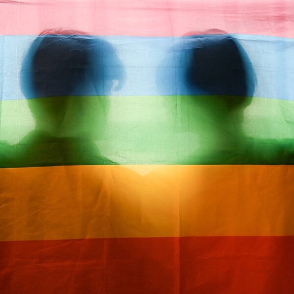 regenboogvlag met daarachter de schaduw van 2 mannen